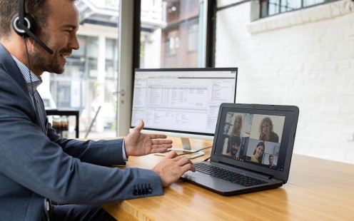 Ein junger Steuerberater hält im Büro eine Videokonferenz mit Mandanten